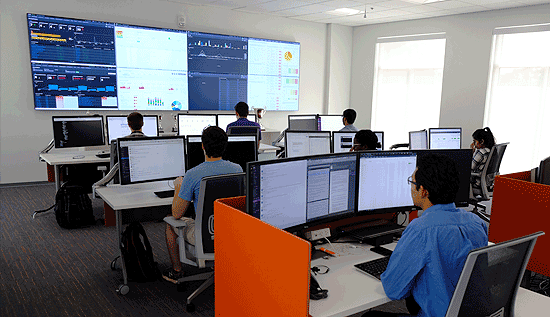 Several people working at computers with a large display wall at the front of room